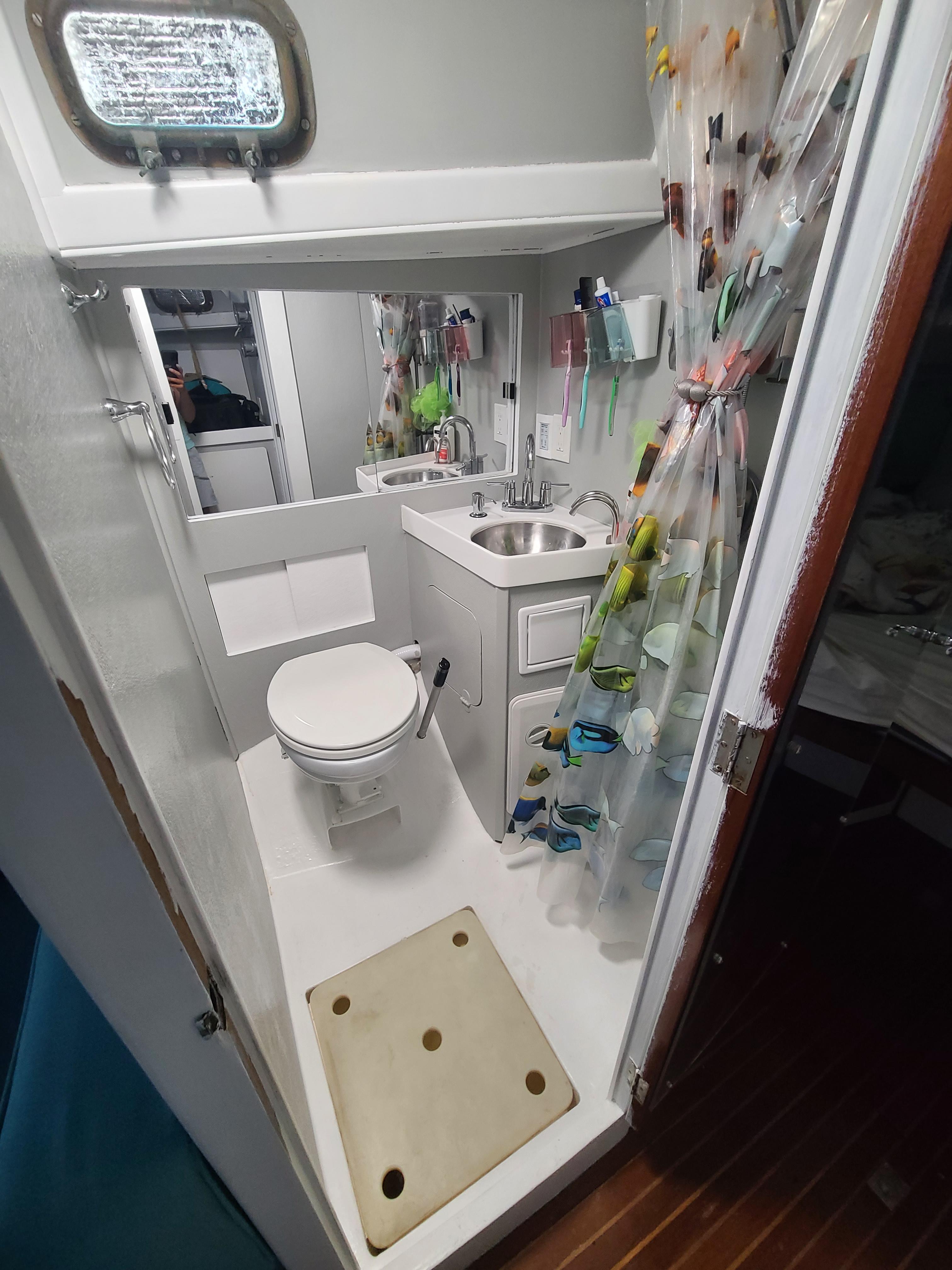 Slide: The Image of Compact bathroom in a 1981 Kelly Peterson 44 sailboat, featuring a toilet, sink, and shower. - 40