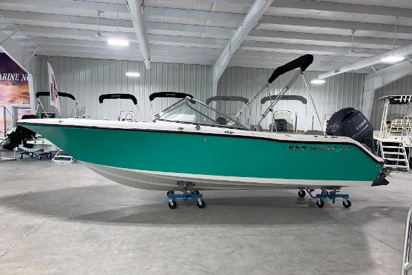 Slide: The Image of 2024 Key West 203 DFS boat in showroom, teal hull, black canopy, outboard motor. - 0