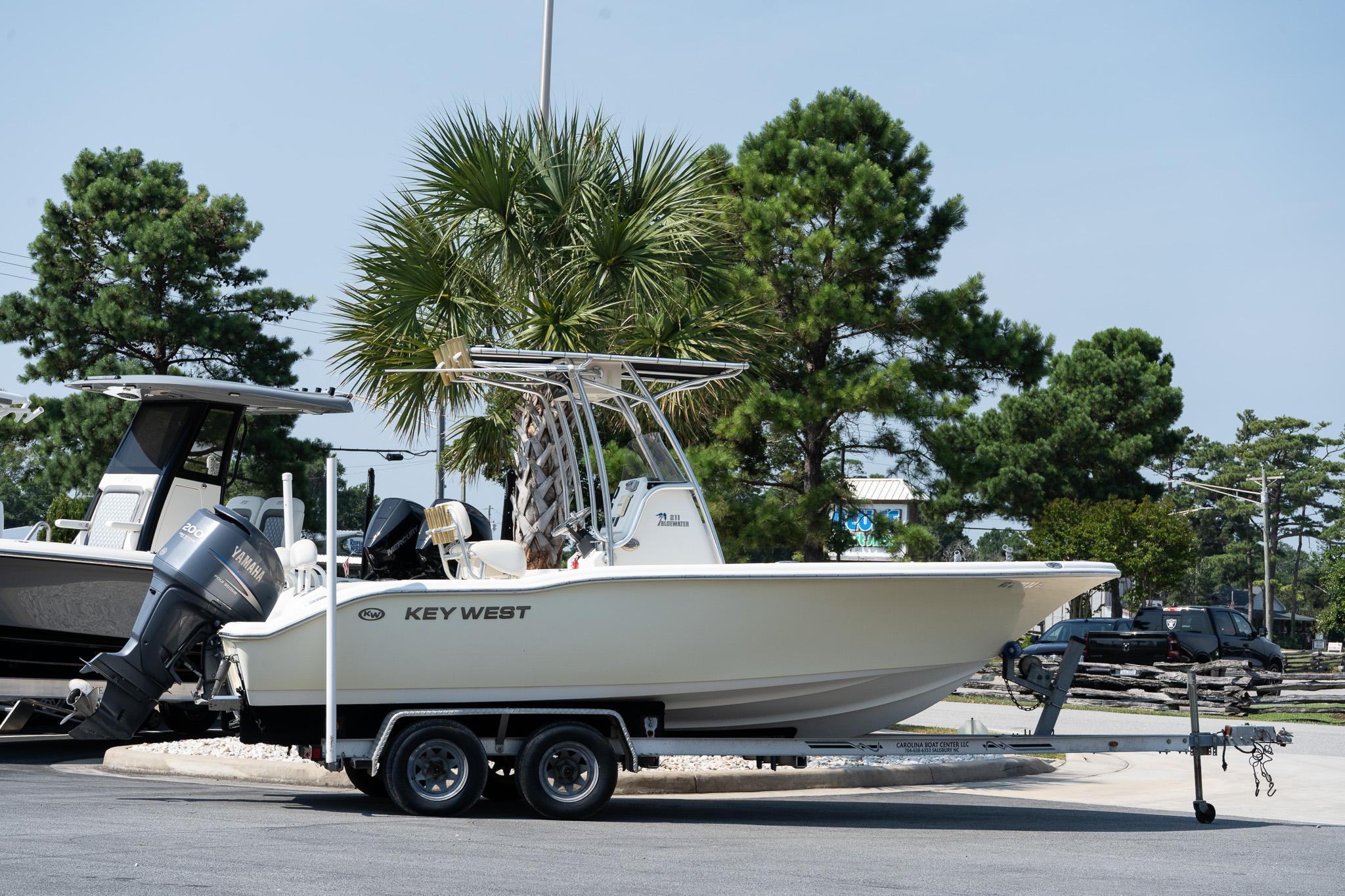 The Image of 2008 Key West 211 Center Console boat on trailer, parked near palm trees. - 0