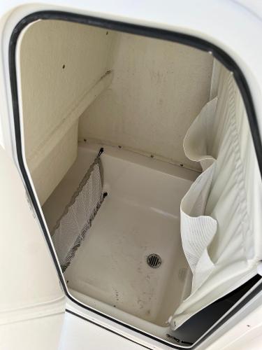 Slide: The Image of 2026 Key West 219 FS boat interior storage compartment with netting and drain. - 7