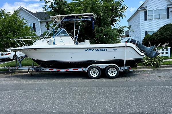 Slide: The Image of 2005 Key West 2300 WA boat on a trailer in a residential area. - 0