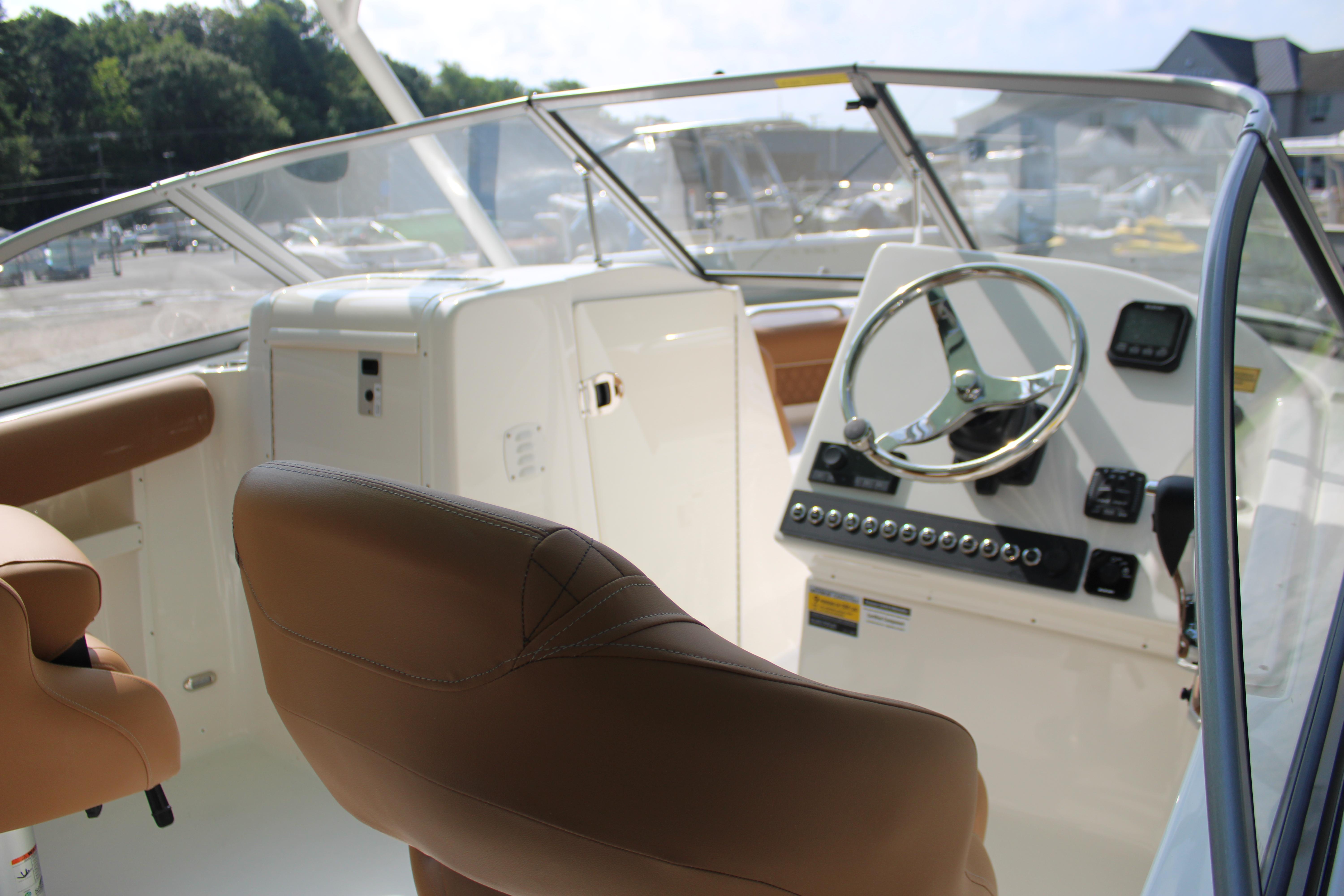 Slide: The Image of 2026 Key West 239 DFS boat interior with steering wheel and tan seating. - 10