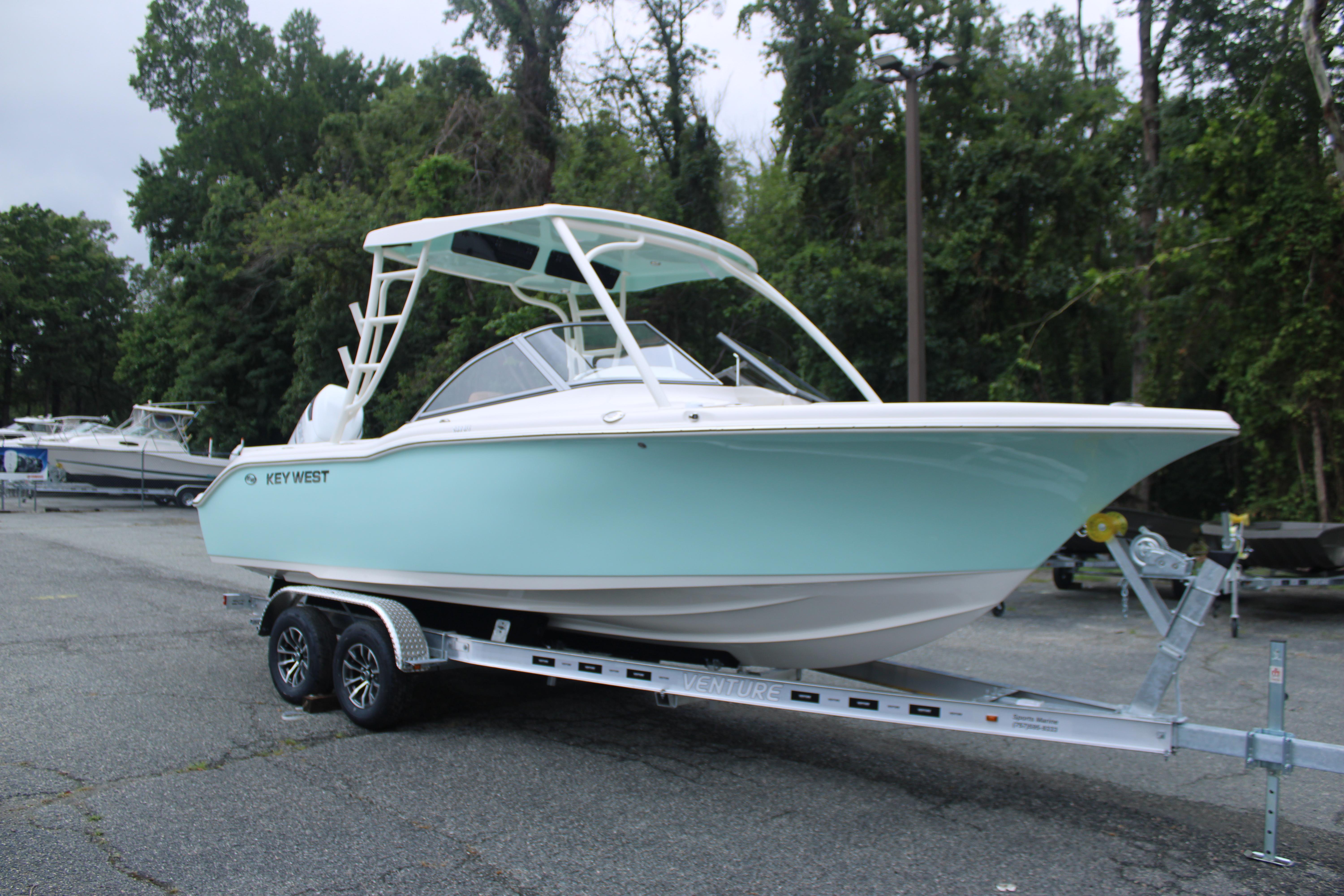 Slide: The Image of 2026 Key West 239 DFS boat on trailer, parked outdoors, surrounded by trees. - 3