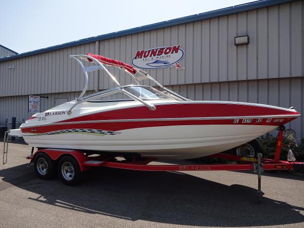 Slide: The Image of 2007 Larson 206 Senza boat on trailer, red and white design, parked outside Munson building. - 2