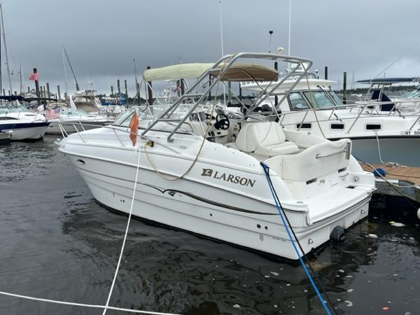 Slide: The Image of 2002 Larson 254 Cabrio boat docked in a marina on a cloudy day. - 1