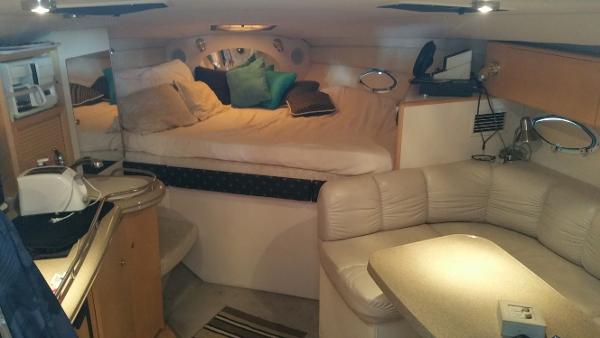 Slide: The Image of 2003 Larson 330 CABRIO boat interior with cozy bed, kitchenette, and seating area. - 16