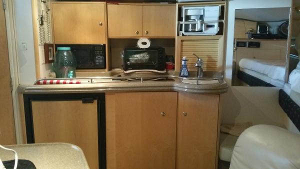 Slide: The Image of 2003 Larson 330 CABRIO boat interior kitchen with wooden cabinets and appliances. - 17