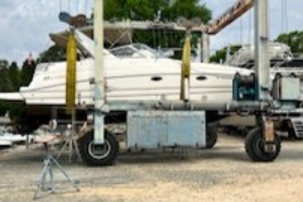 Slide: The Image of 2003 Larson 330 Cabrio boat on a lift, surrounded by trees and equipment. - 26