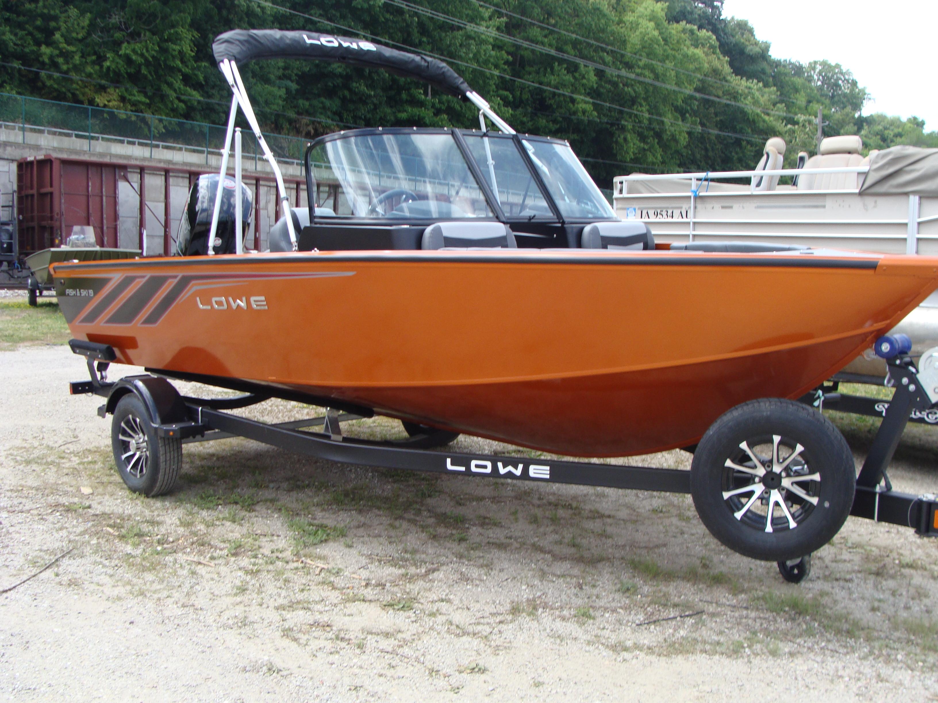 Slide: The Image of 2023 Lowe FS 1900 boat on trailer, orange hull, parked outdoors. - 3