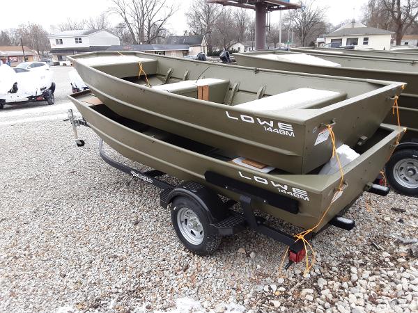 Slide: The Image of 2024 Lowe Jon L1448 boats on a trailer in a gravel lot. - 2