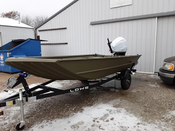 Slide: The Image of 2024 Lowe Roughneck 1660 boat on trailer outside a metal building in winter. - 1