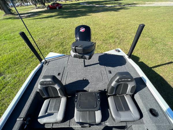 Slide: The Image of 2024 Lowe Stinger 188 SC fishing boat with dual seats and motor on grassy field. - 4