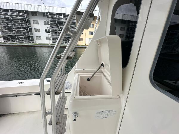 Slide: The Image of 1993 Luhrs 320 Tournament boat with open storage compartment, docked near modern buildings. - 11
