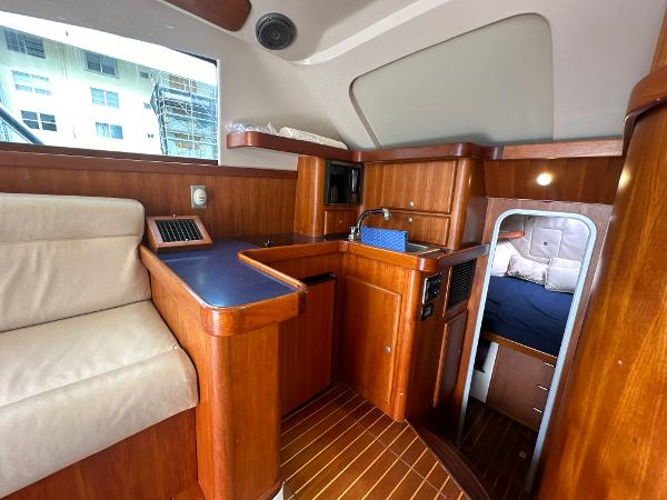 Slide: The Image of 1993 Luhrs 320 Tournament cabin interior with wood finish, seating, and compact kitchen area. - 19