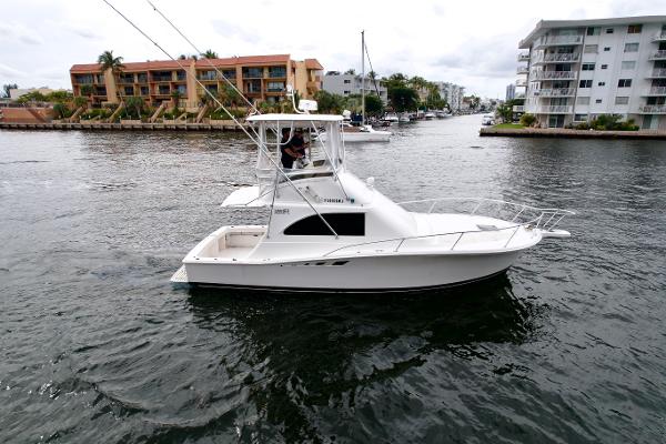 Slide: The Image of 1993 Luhrs 320 Tournament boat cruising in a canal near waterfront buildings. - 2