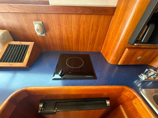 Slide: The Image of 1993 Luhrs 320 Tournament yacht kitchen with stove and wooden cabinetry. - 21