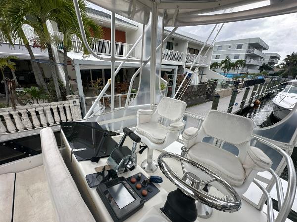 Slide: The Image of 1993 Luhrs 320 Tournament boat cockpit with steering wheel and controls, docked near waterfront homes. - 29