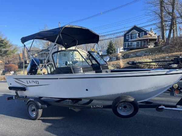 Slide: The Image of 2024 Lund 1650 Angler Sport boat on trailer with canopy in residential area. - 2