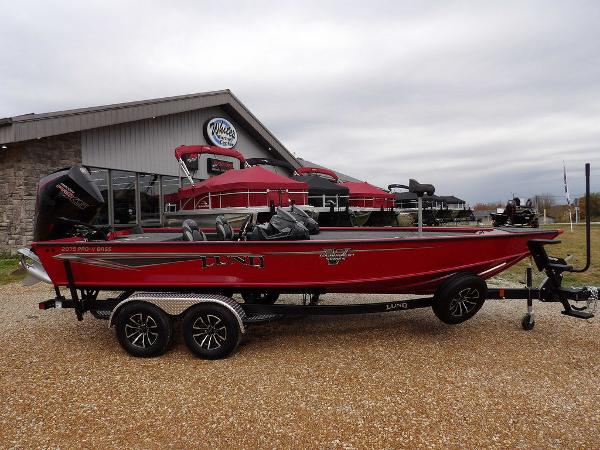 Slide: The Image of 2024 Lund 2075 Pro-V Bass XS boat in red, parked on a trailer outside a dealership. - 4