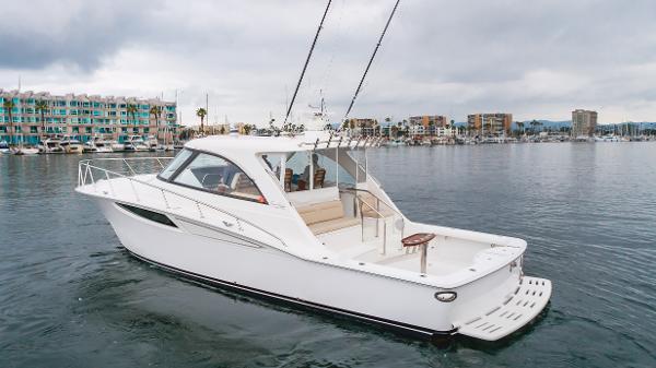 Slide: The Image of 2023 Mag Bay 42 Express yacht on calm water, with marina and buildings in the background. - 20