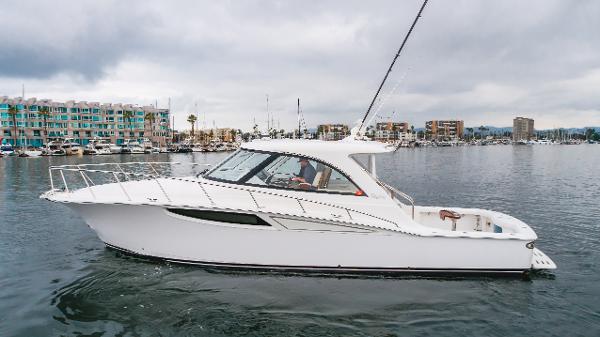 Slide: The Image of 2023 Mag Bay 42 Express yacht cruising in a marina with modern buildings in the background. - 21
