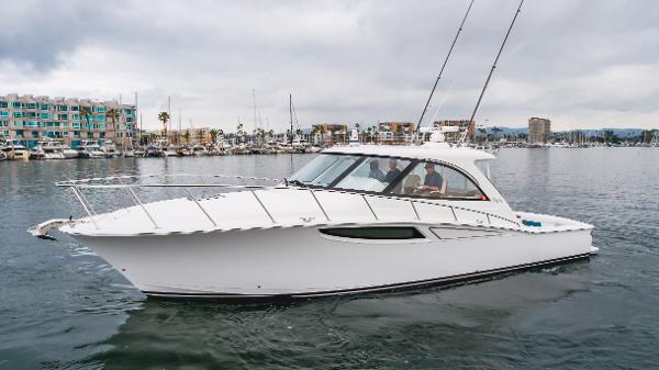 Slide: The Image of 2023 Mag Bay 42 Express yacht cruising in a marina with modern buildings in the background. - 22