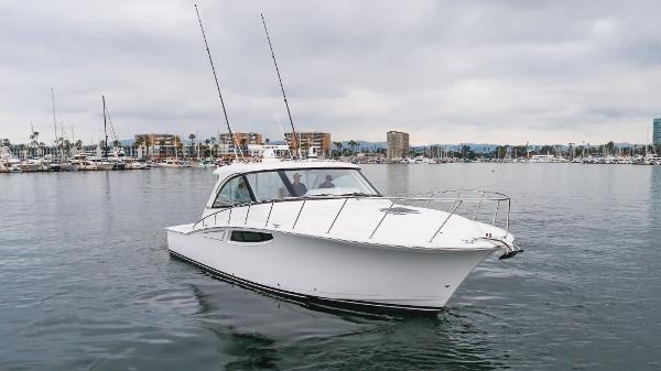 Slide: The Image of 2023 Mag Bay 42 Express boat on calm water, overcast sky, marina in background. - 25