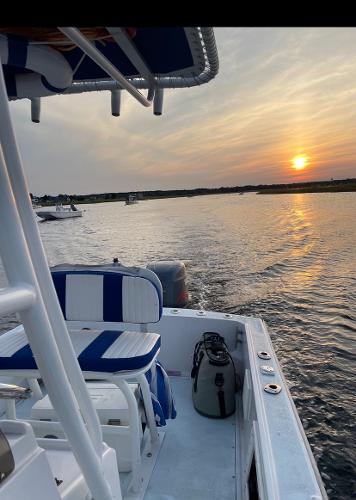 Slide: The Image of 1980 Mako 23 boat on water at sunset, featuring blue and white seating. - 12
