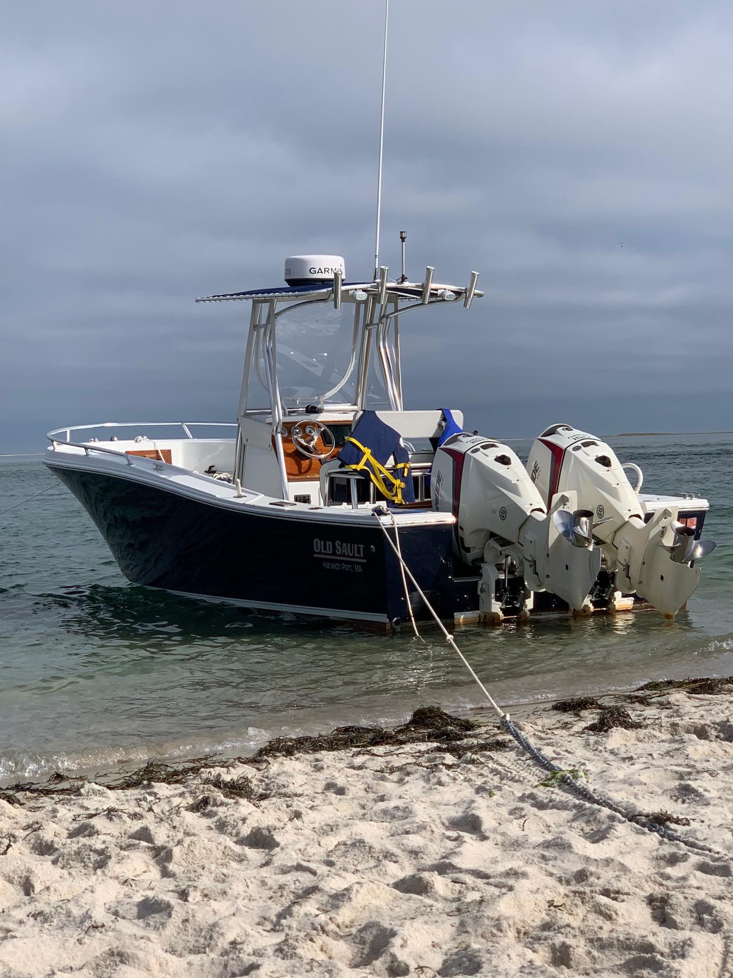 Slide: The Image of A 1991 Mako 241 boat anchored on a sandy beach with dual outboard motors. - 1