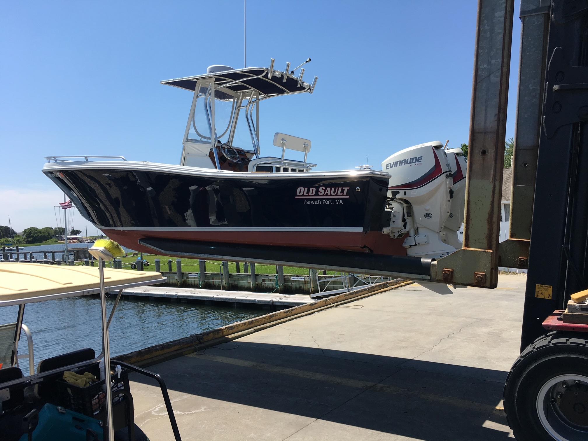 Slide: The Image of 1991 Mako 241 boat lifted by forklift at marina, featuring Evinrude engine. - 29