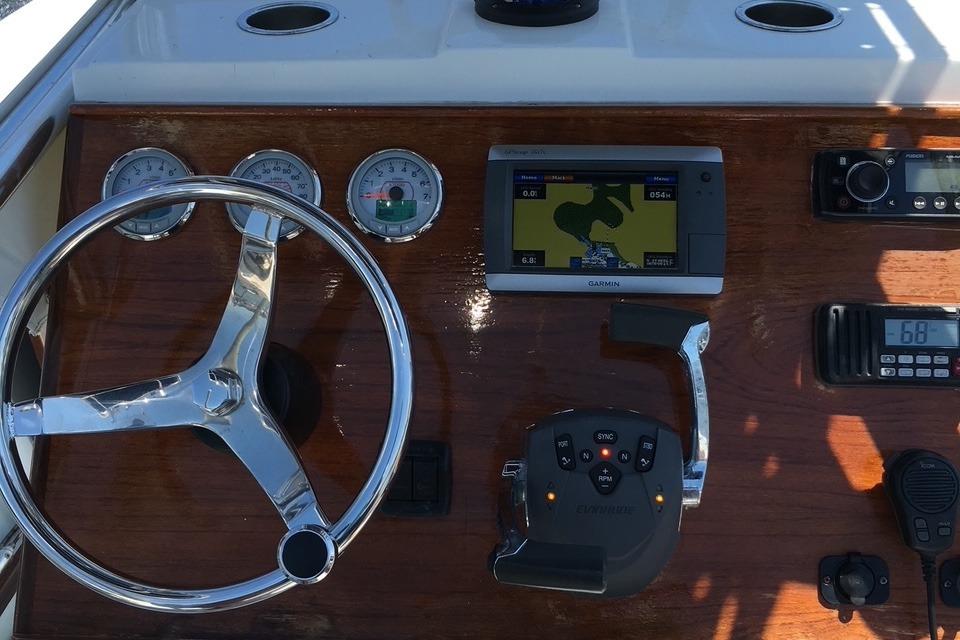 Slide: The Image of 1991 Mako 241 boat dashboard with steering wheel, gauges, GPS, and radio controls. - 5