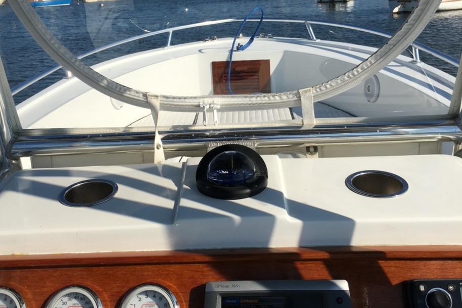 Slide: The Image of 1991 Mako 241 boat dashboard with compass, cup holders, and gauges on a sunny day. - 6