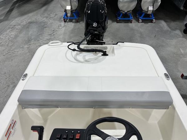 Slide: The Image of 2023 Mako Pro Skiff 13 CC boat interior with steering wheel and outboard motor. - 12
