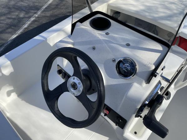 Slide: The Image of 2024 Mako Pro Skiff 13 CC steering console with black wheel and control panel. - 4