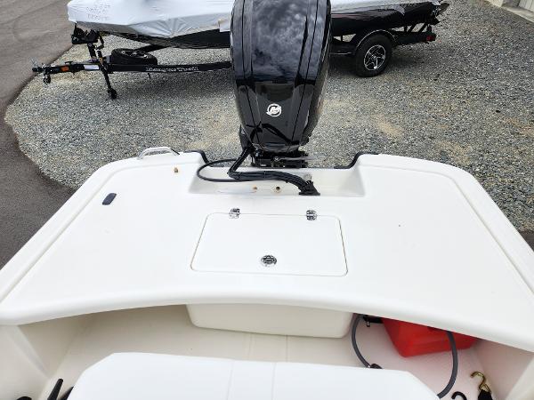 Slide: The Image of 2024 Mako Pro Skiff 17 CC boat stern with outboard motor and storage compartment. - 5