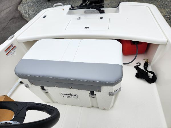 Slide: The Image of 2024 Mako Pro Skiff 17 CC boat interior with storage compartment and cushioned seat. - 6
