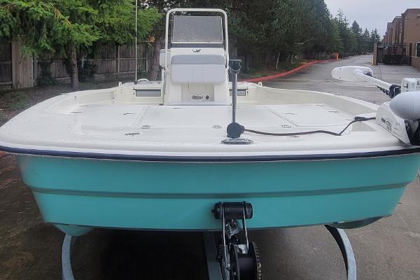 Slide: The Image of 2024 Mako Pro Skiff 19 CC boat on trailer, front view, teal hull, white deck. - 1