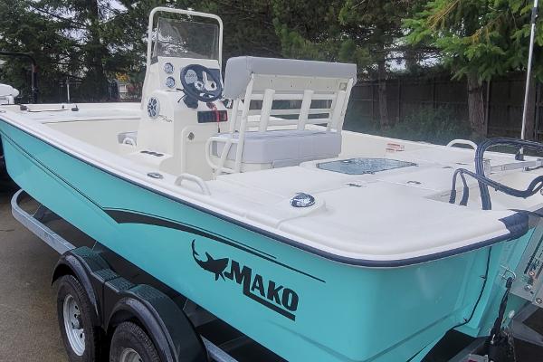 Slide: The Image of 2024 Mako Pro Skiff 19 CC boat on trailer, side view with console and seating. - 3