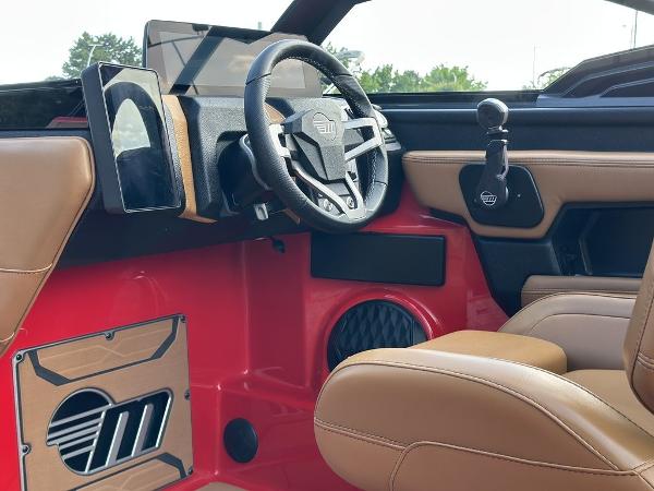 Slide: The Image of Interior of 2025 Malibu 23 LSV boat with modern steering and tan seats. - 16