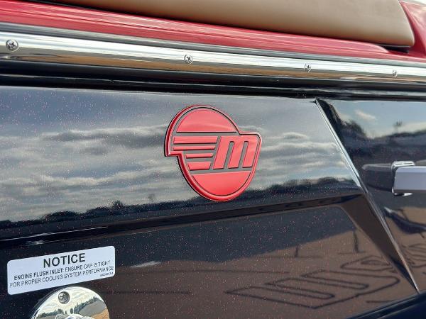 Slide: The Image of 2025 Malibu 23 LSV boat with red logo and notice label on black surface. - 3