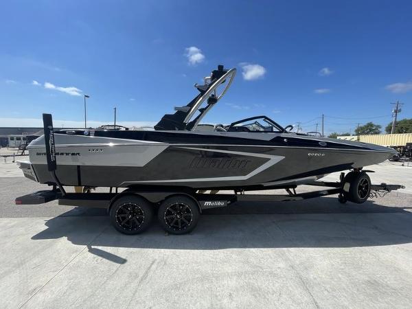 Slide: The Image of 2023 Malibu 24 MXZ boat on a trailer under a clear blue sky. - 1