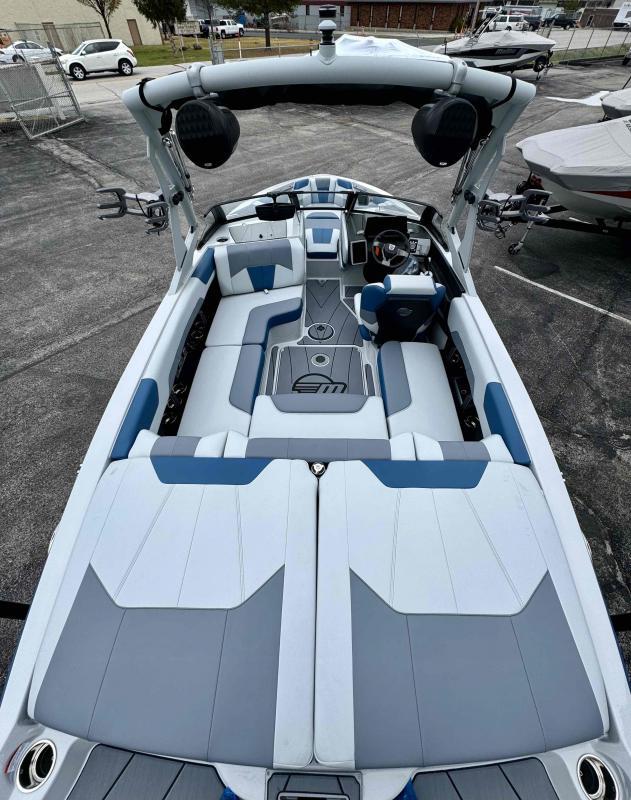 Slide: The Image of 2024 Malibu 20 VTX boat interior with blue and white seating, advanced dashboard, and tower speakers. - 12