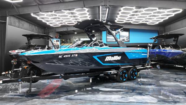 Slide: The Image of 2021 Malibu Wakesetter 24 MXZ boat in showroom, sleek design, vibrant blue accents. - 1