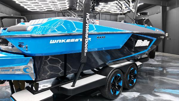 Slide: The Image of 2021 Malibu Wakesetter 24 MXZ in vibrant blue, showcased indoors on a trailer. - 14