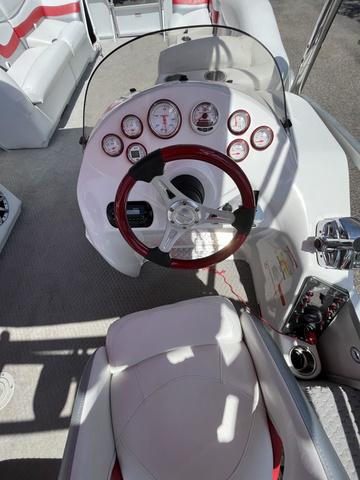 Slide: The Image of 2008 Manitou 24 X-Plode Cruise boat dashboard with red-accented steering wheel and gauges. - 11