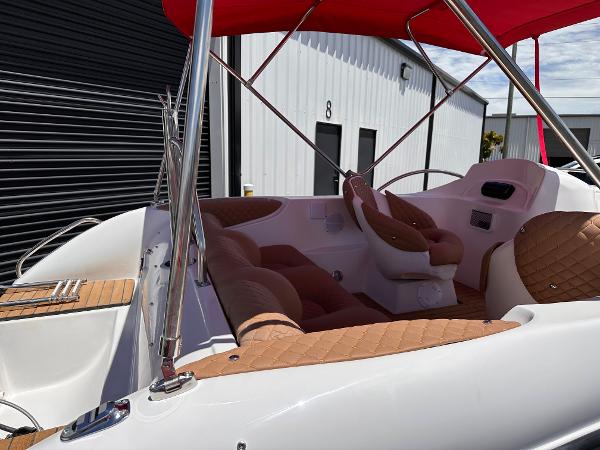 Slide: The Image of 2025 MarinBoat Tango with red canopy and tan seating, docked near industrial building. - 4