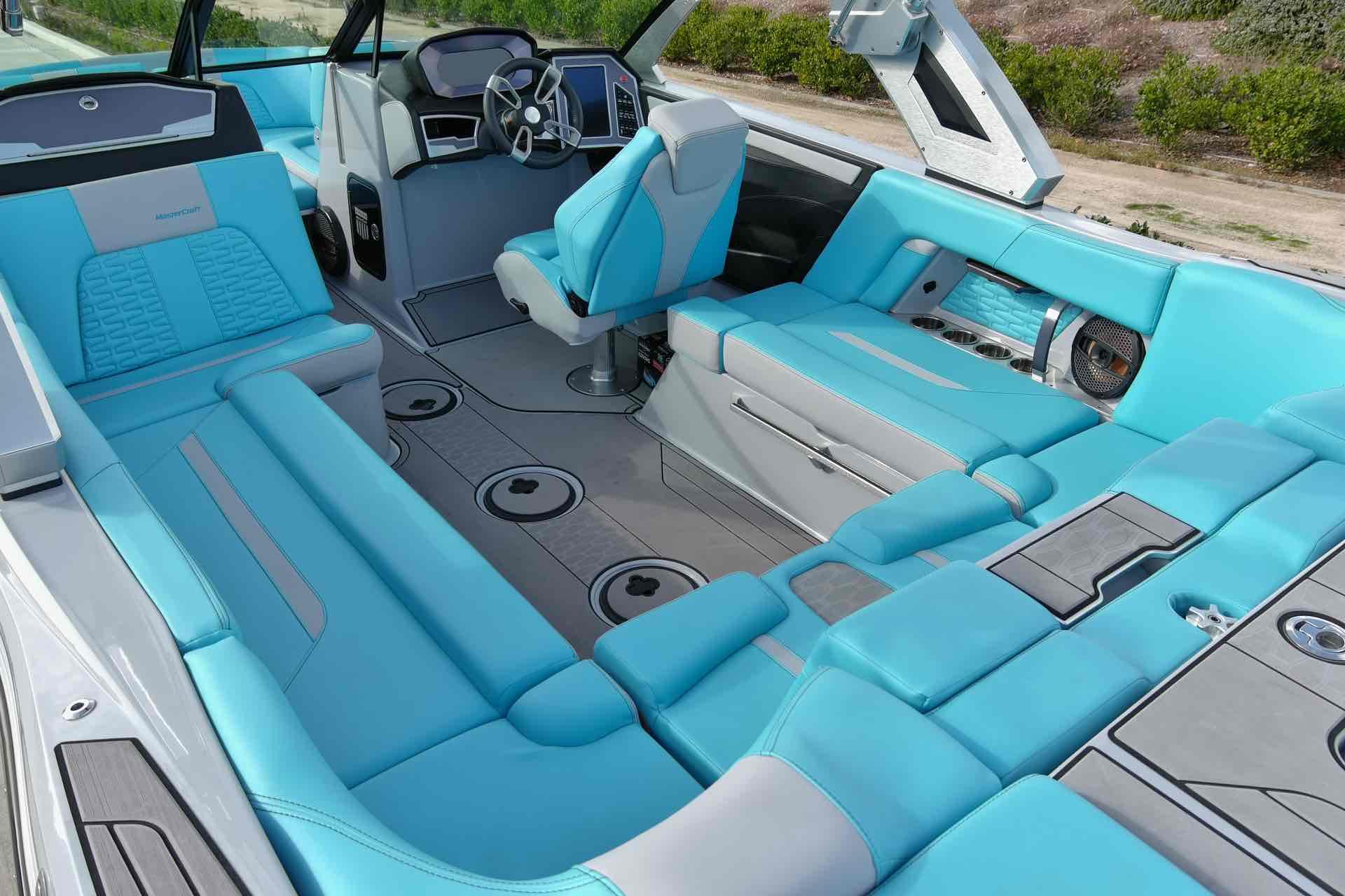 Slide: The Image of 2023 MasterCraft X22 boat interior with turquoise and gray seating, modern dashboard, and ample storage. - 10