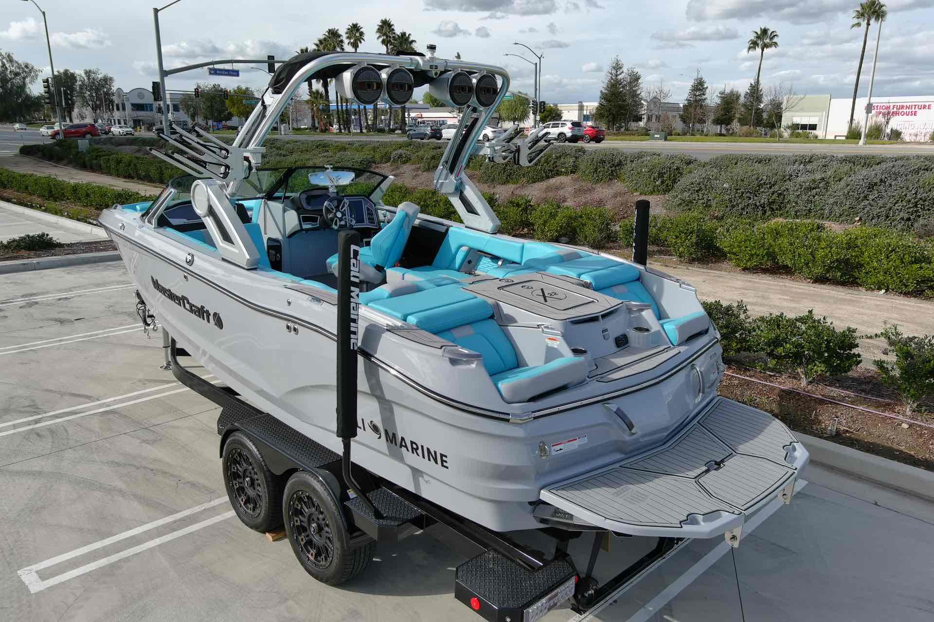 Slide: The Image of 2023 MasterCraft X22 boat with blue interior on a trailer in a parking lot. - 3