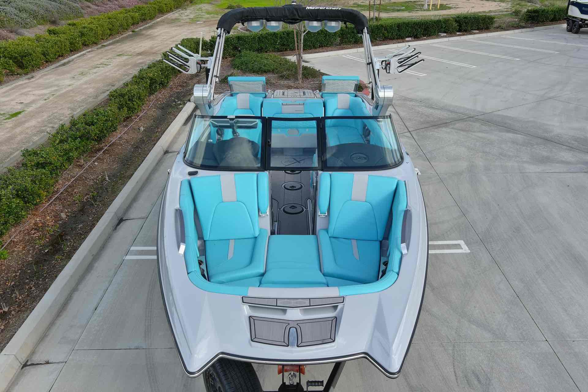 Slide: The Image of 2023 MasterCraft X22 boat with blue and gray interior, parked in a lot. - 6