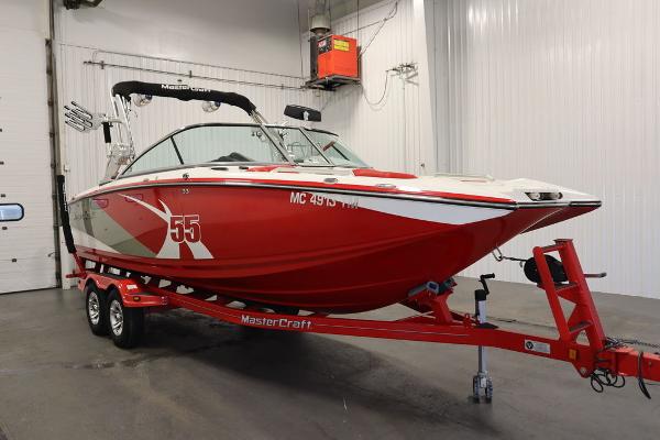 Slide: The Image of 2013 MasterCraft X55 red boat on trailer in indoor storage. - 2